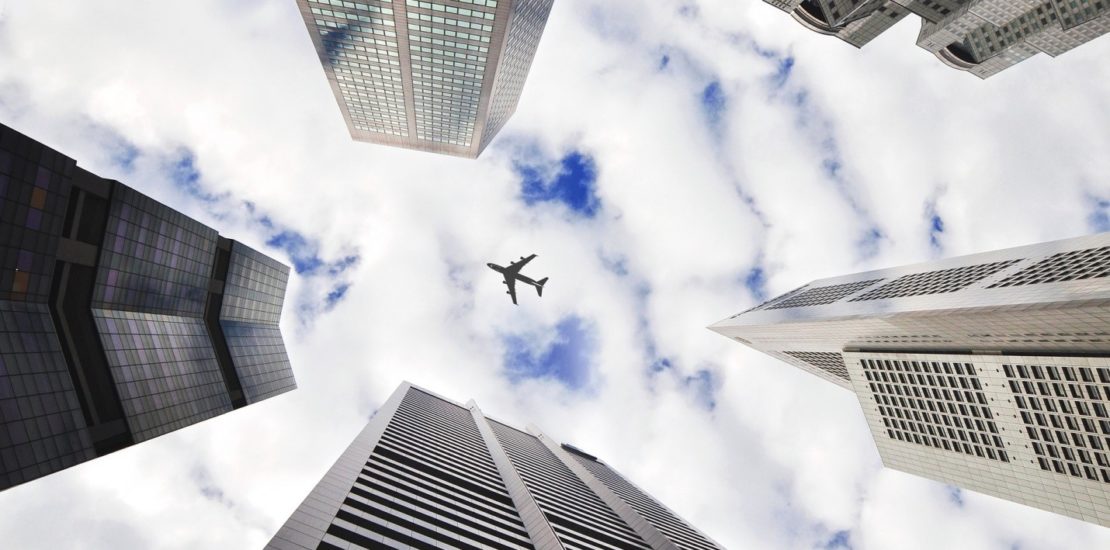 Plane flying above multiple tall buildings